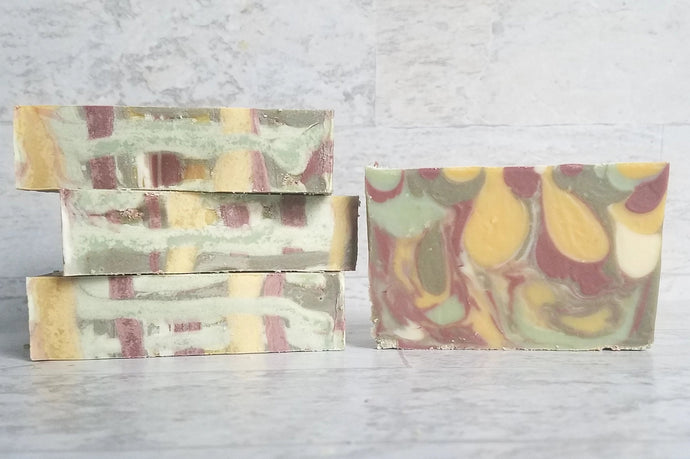 Multi colored artisan cold process soap with red, yellow, white, and green drop swirls and the top looks like woven tweed.